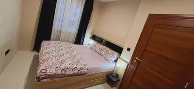 a small bedroom with a bed and a wooden door at Apartman Laki-M in Belgrade