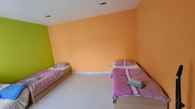two beds in a room with green and orange walls at Apartman Laki-M in Belgrade