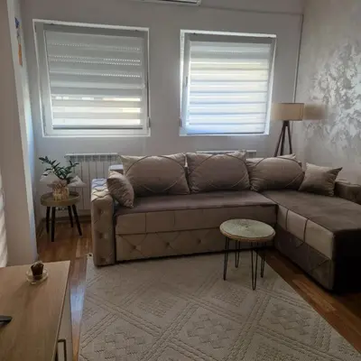 a living room with a couch and two windows at Stylish and cozy stay in Belgrade