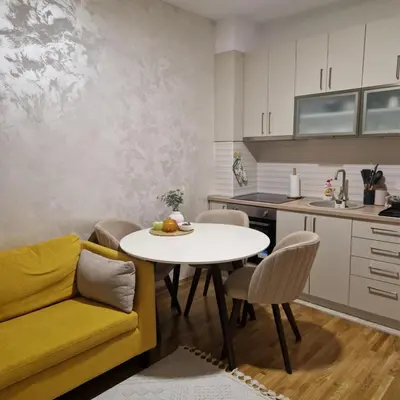 a kitchen and living room with a table and a yellow couch at Stylish and cozy stay in Belgrade