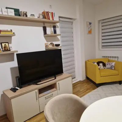 a living room with a television and a yellow chair at Stylish and cozy stay in Belgrade