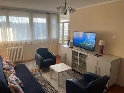a living room with a flat screen tv and blue chairs at Comfort & Style Panoramic Urban Retreat 2 in Belgrade