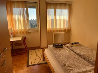 a bedroom with a bed with a radiator and two windows at Comfort & Style Panoramic Urban Retreat 2 in Belgrade
