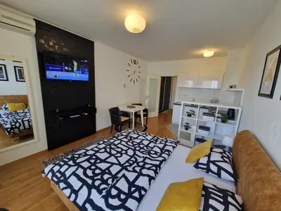 a living room with a bed and a tv on the wall at Apartman Fox in Belgrade
