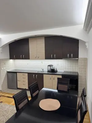 a kitchen with a table and chairs and a counter at Apartman Centar in Obrenovac