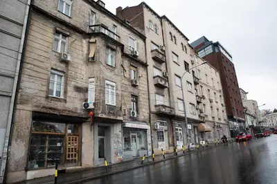 a city street with buildings on a rainy street at Astra Apartment in Belgrade