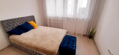 a bedroom with a bed with blue pillows and a window at Apartman Vojvoda in Belgrade