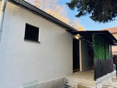 a white house with a door with a green ivy at Vračarska kućica in Belgrade
