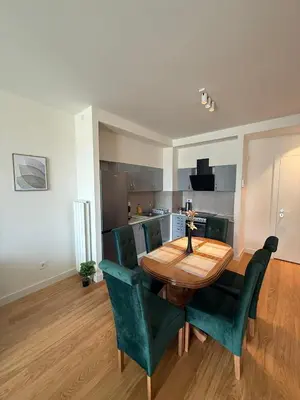 a dining room with a wooden table and green chairs at Q4 Comfort Apartment in Belgrade