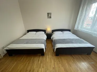 two twin beds in a room with wooden floors at Sunlight House in Belgrade