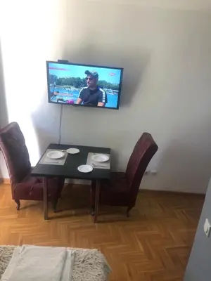 a living room with a table and a tv on the wall at Visoki Stevan Apartments in Belgrade
