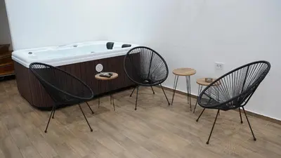 a hot tub sitting in a room with three chairs at Jacuzzi Sensation in Belgrade