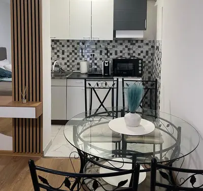 a glass table and chairs in a kitchen with a counter at Apartman Lučiano Aranđelovac in Arandjelovac