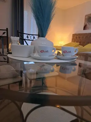 a glass table with two cups and saucers on it at Apartman Lučiano Aranđelovac in Arandjelovac