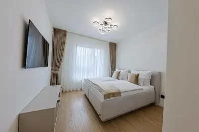 a white bedroom with a bed and a chandelier at ZIGZAG Belgrade Waterfront - SIMFONIJA 2 in Belgrade