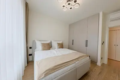 a white bedroom with a bed and a chandelier at ZIGZAG Belgrade Waterfront - SIMFONIJA 2 in Belgrade