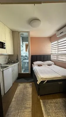 a bedroom with a large bed and a kitchen at A tiny single room - Macchiato in Belgrade