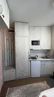 a kitchen with white cabinets and a sink at A tiny single room - Macchiato in Belgrade
