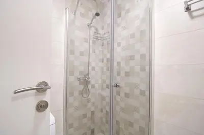 a shower stall with a glass door with a shower head at Studio Apartman Valdez 1 in Belgrade