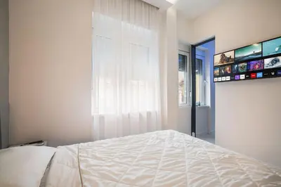 a white bedroom with a bed and a window at Prime Location Modern Luxury in Bohemian Skadarlija! in Belgrade