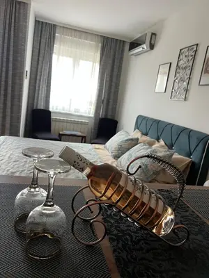 a table with two wine glasses and a bottle on it at Mama in Belgrade