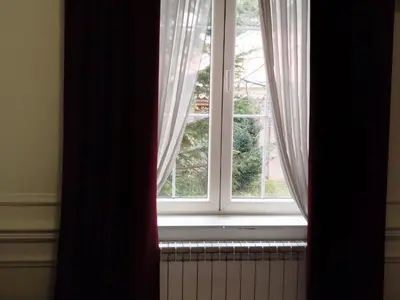 a window with curtains and a radiator in a room at Apartman V Dedinje in Belgrade
