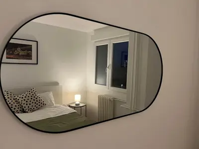 a mirror reflecting a bedroom with a bed and a window at Sassy in Belgrade