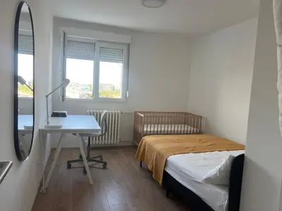 a bedroom with a bed and a desk and window at Sassy in Belgrade
