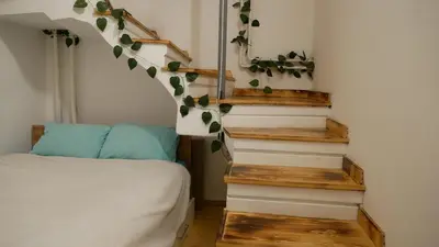 a bedroom with a bed and stairs with leaves on the wall at Terazije apartment in Belgrade