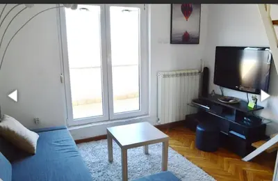 a living room with a blue couch and a tv at Vesna apartment in Belgrade