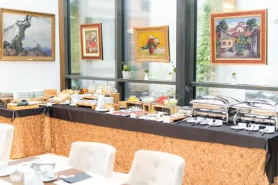 a buffet of food on a table with white chairs at Envoy Hotel in Belgrade