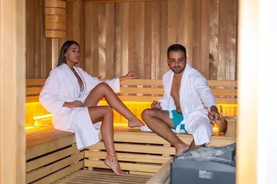 a man and woman sitting on a bed in a sauna at Envoy Hotel in Belgrade