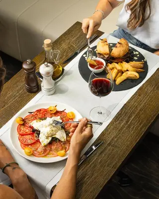 a table with a plate of food and a glass of wine at Envoy Hotel in Belgrade