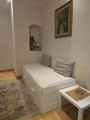 a small bedroom with a bed and a table at Apartment Eleon in Belgrade