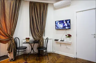 a room with a table and chairs and a television at Belle Apartments - Square 8 in Belgrade
