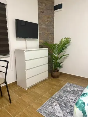 a white dresser with a tv on a wall at Apartman 8 in Ruma