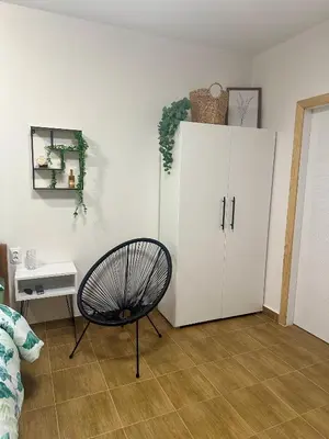 a room with a white cabinet and a chair at Apartman 8 in Ruma