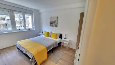 a bedroom with a bed with yellow sheets and two windows at Belgrade City Lux in Belgrade