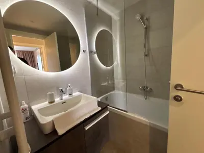 a bathroom with a sink and a shower and a mirror at BW Aqua Lux Premium Apartman in Belgrade