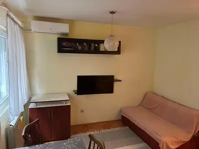 a small room with a bed and a flat screen tv at Apartman S in Belgrade