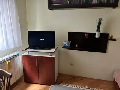 a living room with a tv on a cabinet with a laptop at Apartman S in Belgrade