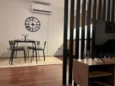 a dining room with a table and a clock on the wall at Liberte Apartments Voždovac in Belgrade