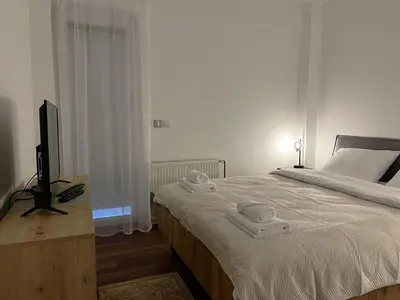 a bedroom with a bed with white sheets and a television at Liberte Apartments Voždovac in Belgrade