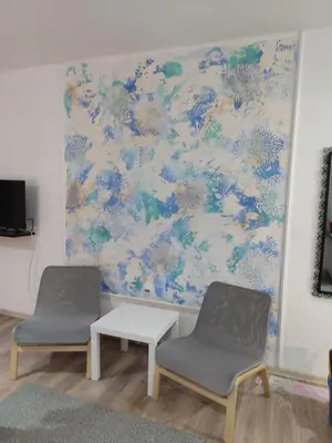 two chairs and a table in front of a wall at Apartman Centar Surcin in Surčin