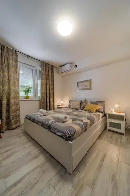 a bedroom with a large bed and a window at Kapetan apartman in Belgrade
