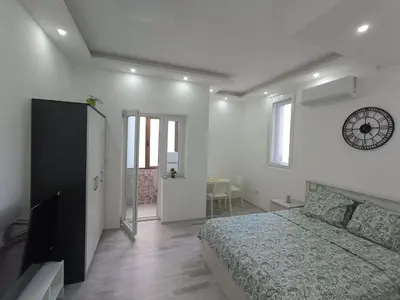 a bedroom with a bed and a clock on the wall at White Apartment Slavija in Belgrade