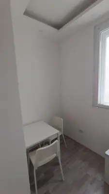 a white room with a table and chairs and a window at White Apartment Slavija in Belgrade