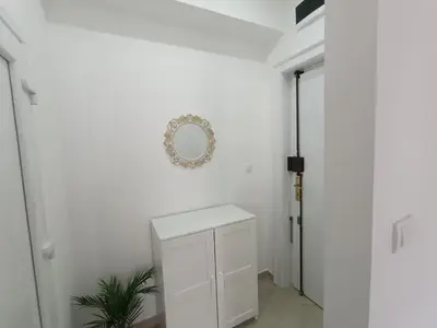 a white hallway with a white cabinet and a mirror at White Apartment Slavija in Belgrade