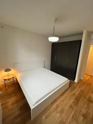 a bedroom with a white bed and a black cabinet at BW Eterna Apartment in Sajmište