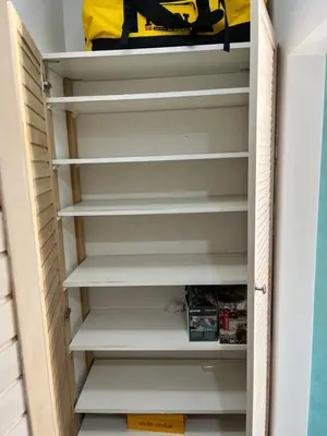 a closet with white shelves and a yellow bag at Gajba Apartment in Belgrade
